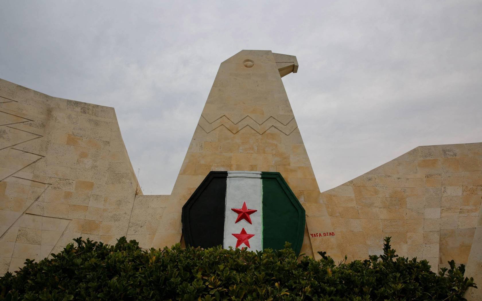 The flag of the Syrian Revolution painted on an eagle-shaped wall in Hama, Syria. 7 December 2024.