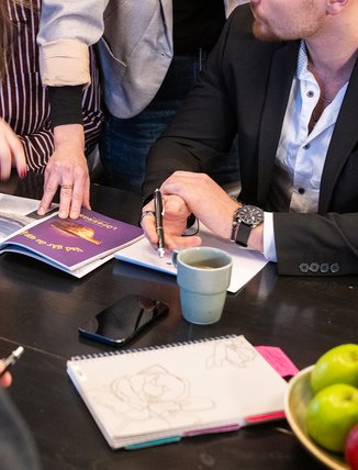 ett arbetslag under konferens kollar p&aring; ett magasin