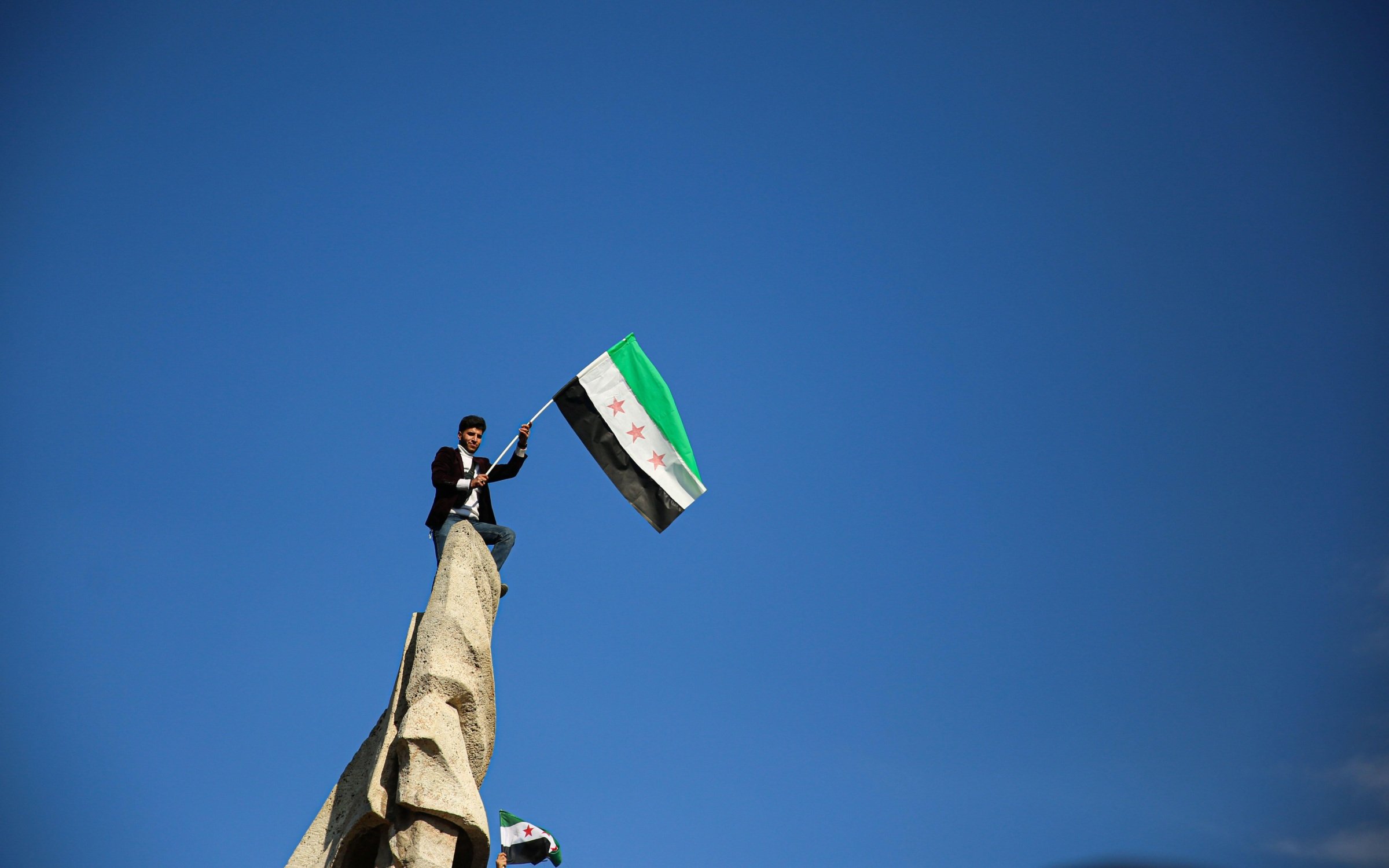 Crowds wave the flag of the Syrian Revolution in Aleppo to celebrate the overthrown of the Assad regime.