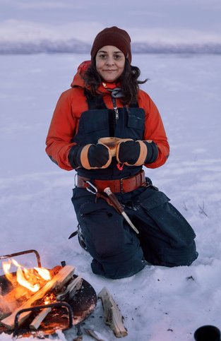 Guide serving traditional Swedish fika by an open fire during a winter adventure in Abisko, Swedish Lapland.