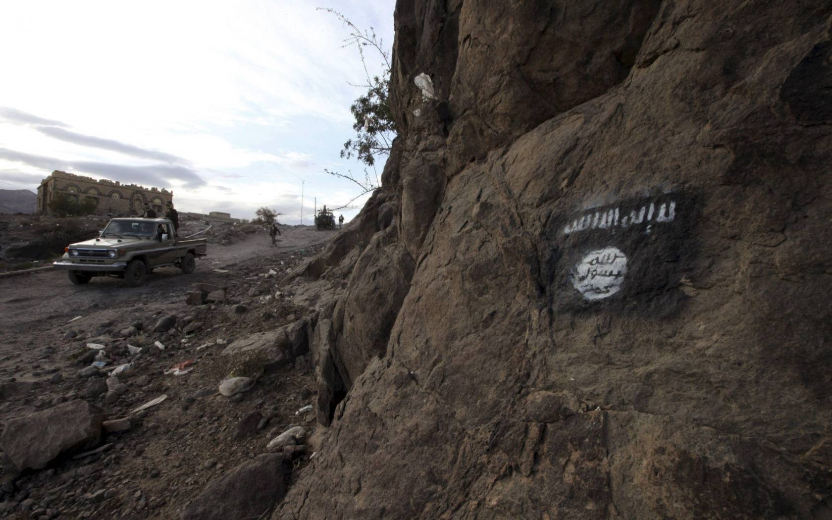Shi'ite Houthi rebels drive a truck past an Ansar al-Sharia flag painted on the side of a hill in Almnash, the main stronghold of the local wing of Al Qaeda in the Arabian Peninsula (AQAP) in Rada, Yemen.