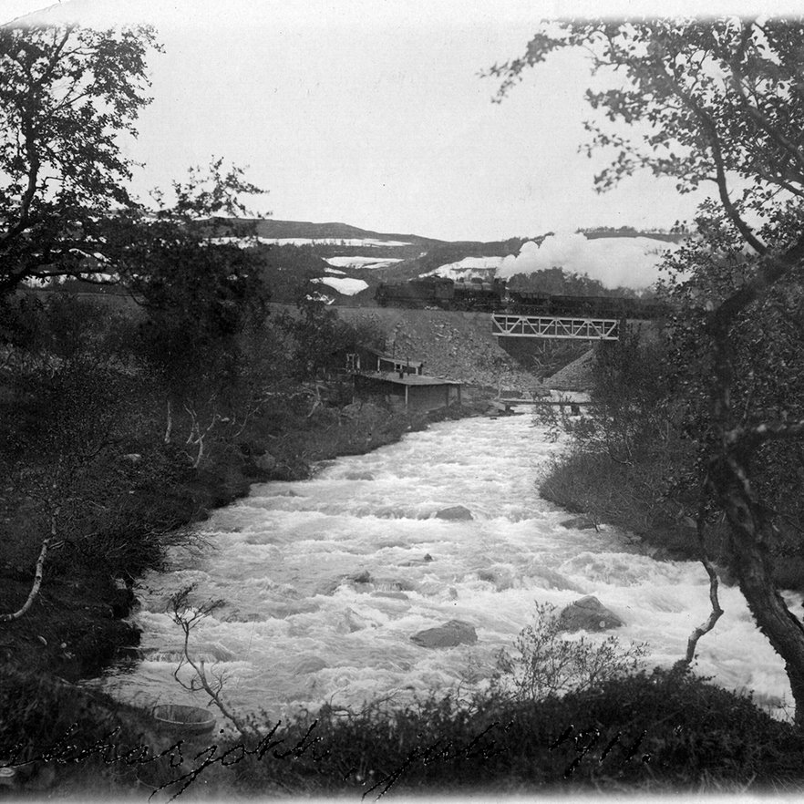 svartvitt fotografi fr&aring;n 1911 p&aring; Rakkasjokk i Bj&ouml;rkliden med ett koleldat lok och malmt&aring;g i bakgrunden