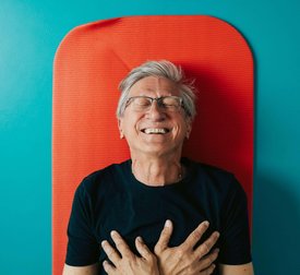 Directly above shot of happy man with hands on chest lying on exercise mat