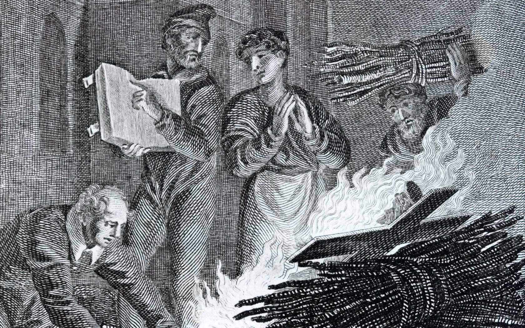 Puritan iconoclasts on the road to Norwich burning a church crucifix in front of the church. A miserable phrygian capped preacher is showing a passage from the bible to a man in a posture of prayer while another man brings more wood for the fire. East Anglia was a centre of iconoclasm in the 17th century