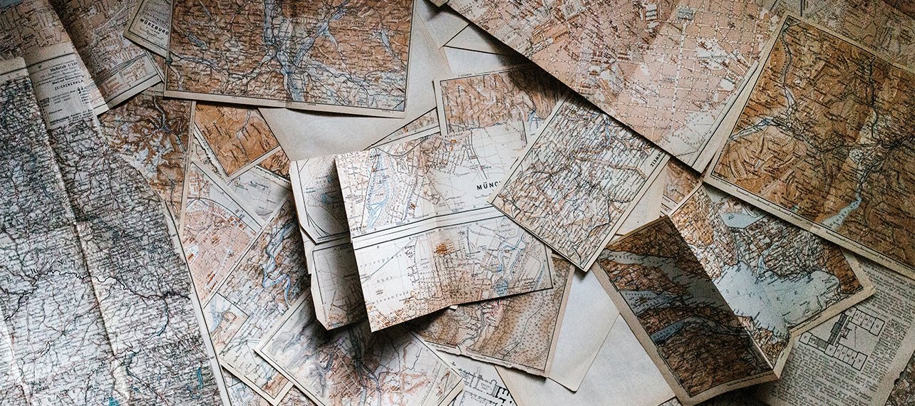 Massor av gamla kartor ligger på ett bord.