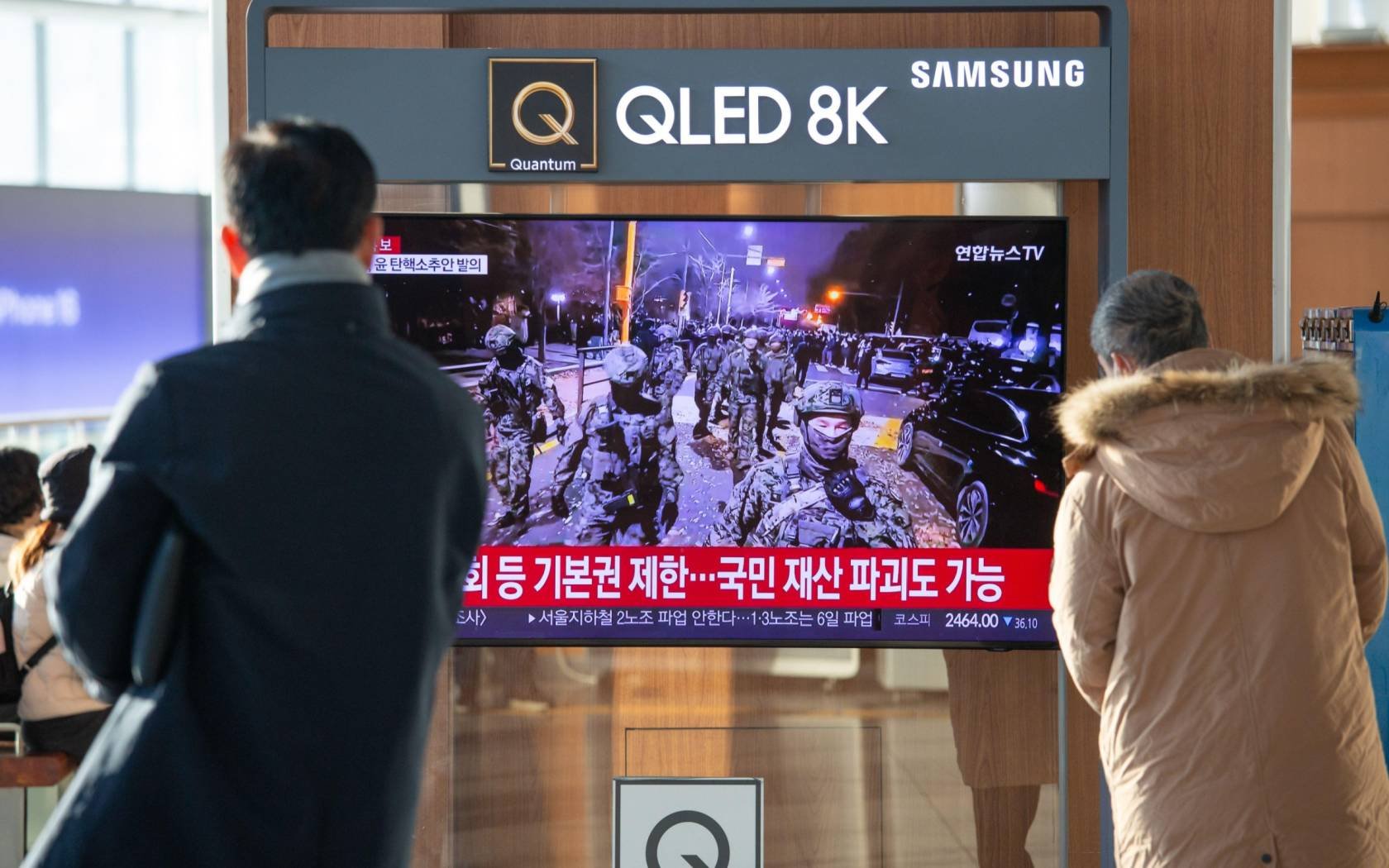 A TV screen at a train station shows a news report on troops entering the parliament building after South Korean President Yoon Suk-Yeol's declaration of martial law