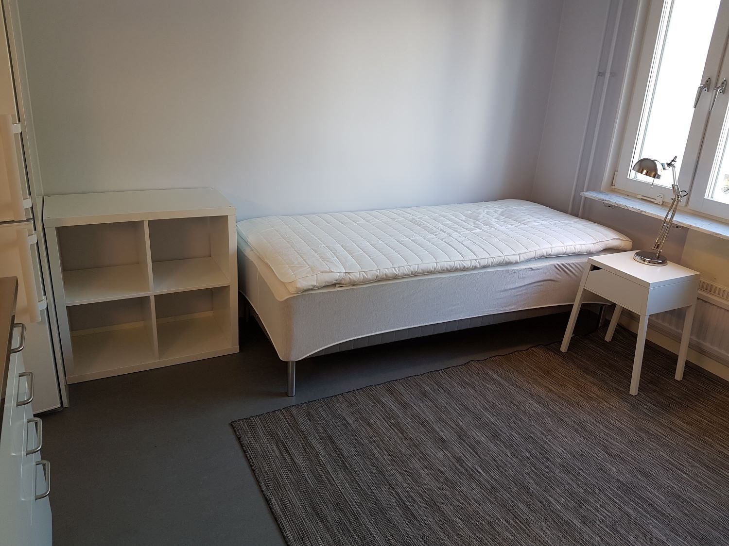 Studentroom with bed, storage unit, bedside table.