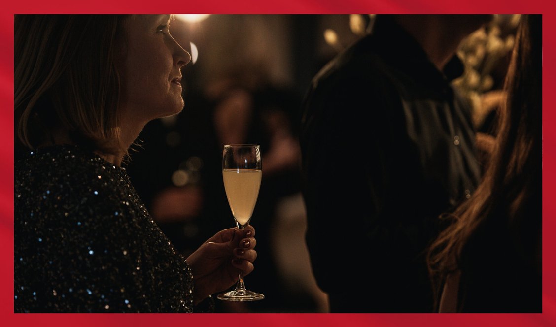 Kvinna med glittrig klänning håller i en cocktail som serveras i ett champagneglas.