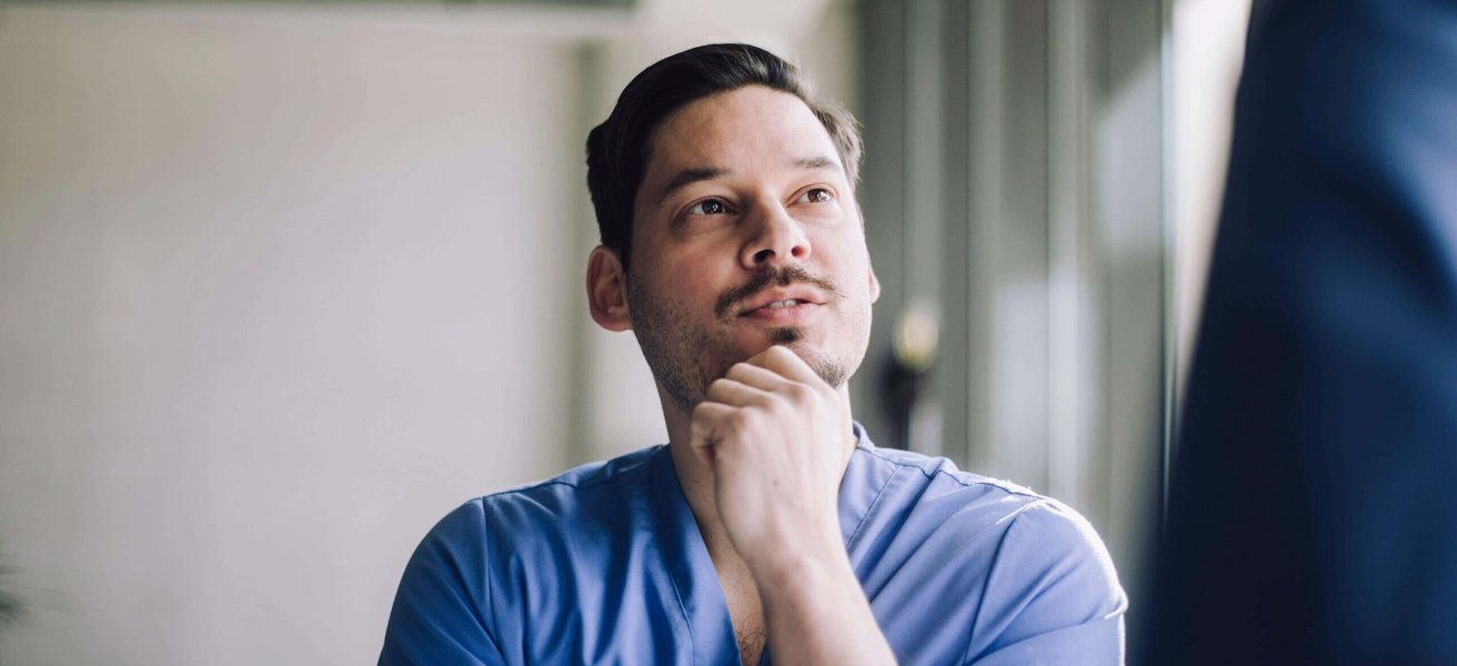 Low angle view of male healthcare professional with hand on chin at hospital