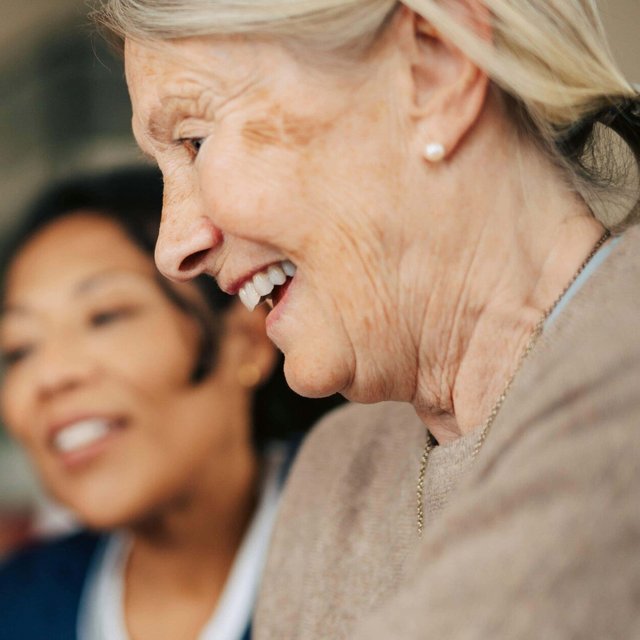 Happy senior woman using smart phone while spending leisure time in retirement home