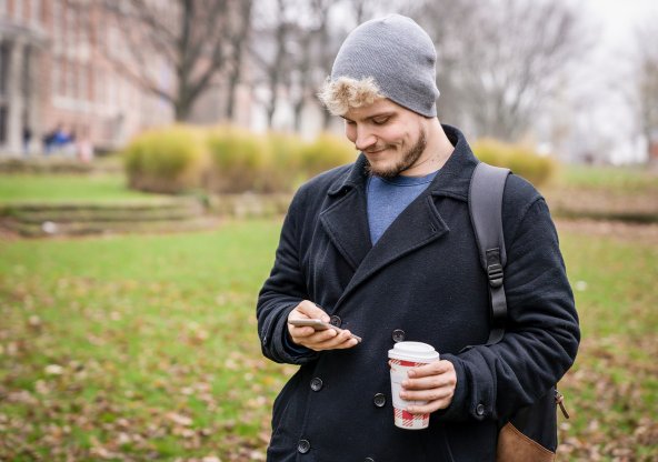 Ung man i parkmiljö, tittar på sin mobil