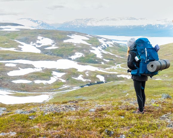 woman looking at snow-covered mountains in early summer