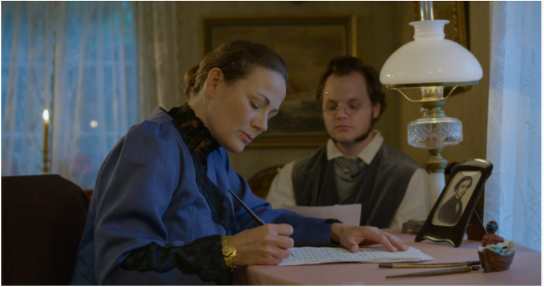 Författarinnan med maken J.G. Carlén, spelade av Camilla Hedin och Daniel Olsson. 