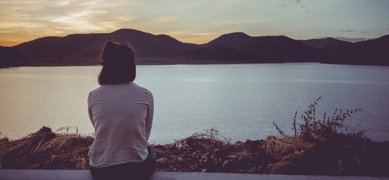 Kvinna med ryggen mot kameran tittar ut över sjö