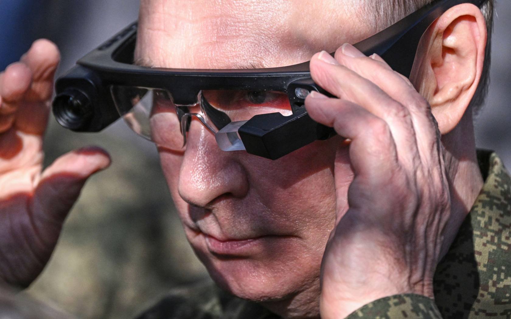 Vladimir Putin tries on thermal imaging goggles as he inspects Russian weapons and equipment.