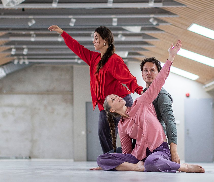 Tre dansare i ett kalt rum med takfönster.