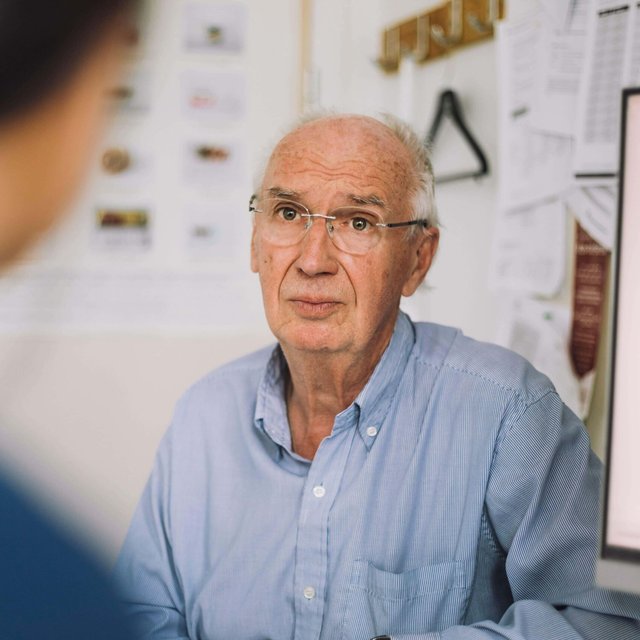Senior male patient wearing eyeglasses and listening to nurse during visit in clinic