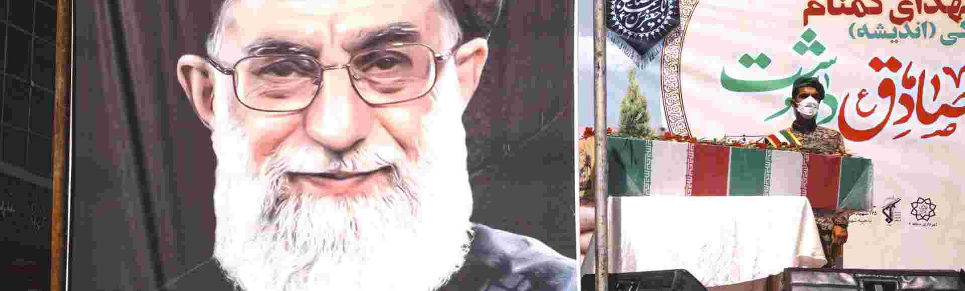 Members of the Islamic Revolutionary Guard Corps (IRGC) stand next to a poster of Ayatollah Khamenei.