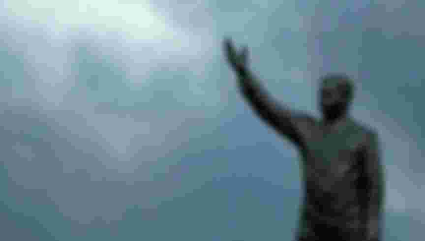 A statue of former Iraqi dictator Sadam Hussein as smoke billows from oil trenches in Baghdad. Credit: Karim Sahib / AFP via Getty Images.