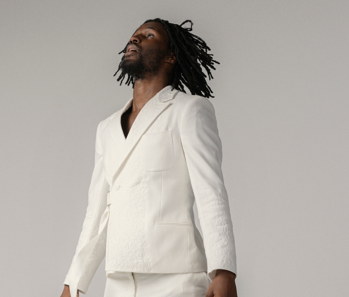 Dansaren hoppar rakt upp i luften med kroppen helt uppsträckt, armarna upp utmed kroppen och tittar upp mot himlen.