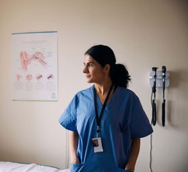 Smiling female doctor standing with hands in pockets at clinic