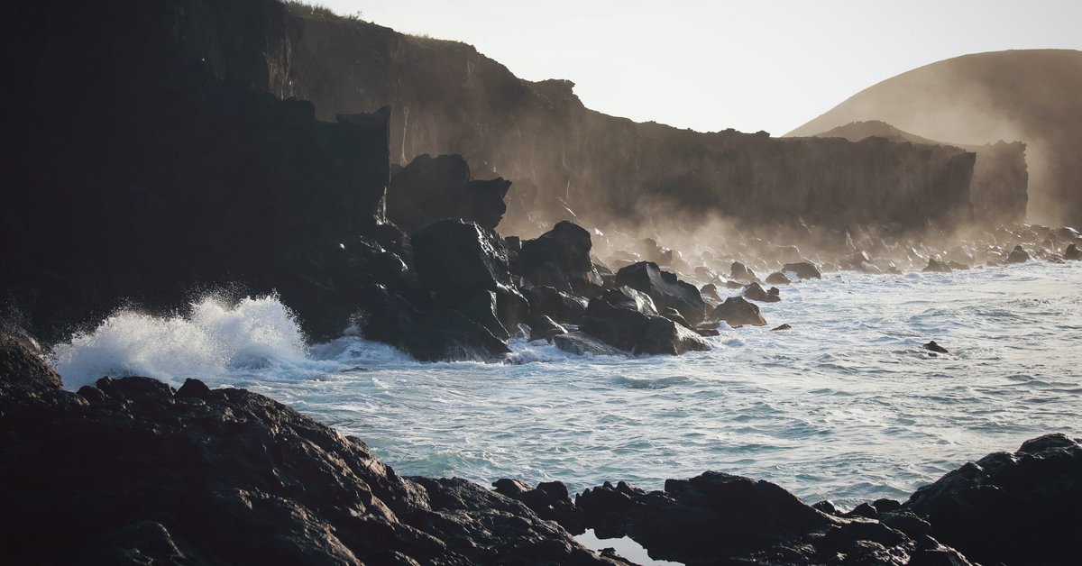 Waves hitting the dark rocks at a beach.
