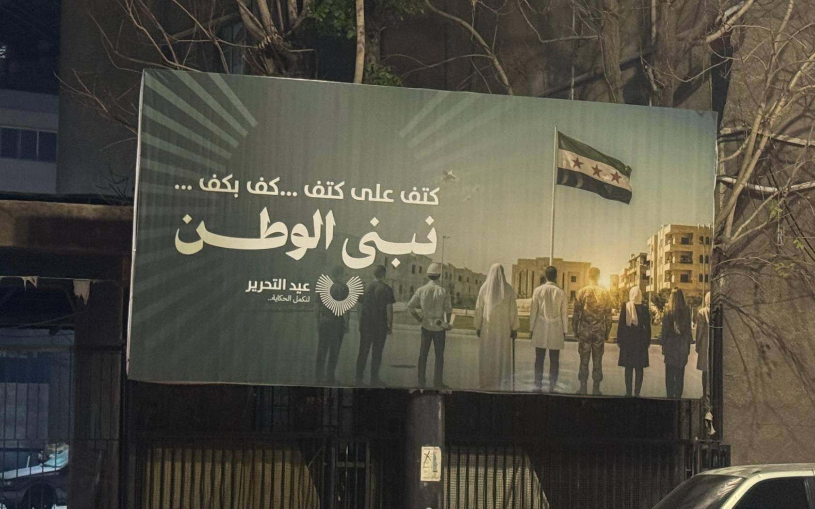 A billboard in Damascus commemorates Syria's 'Liberation Day'. The caption reads: ’Shoulder to shoulder, hand in hand, we build the nation together.’