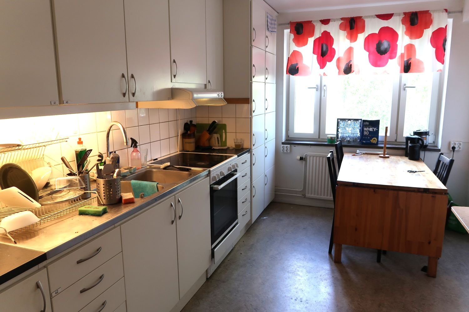 Common kitchen with sink, stove, oven, table, chairs and cupboards.
