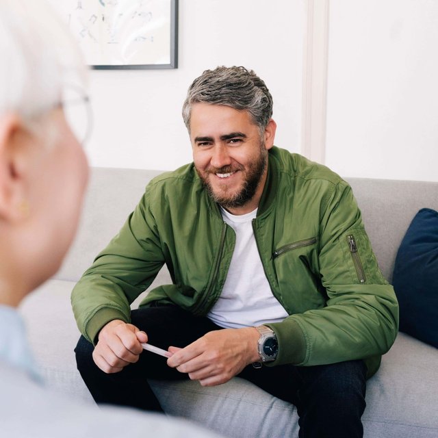 Smiling man talking with female psychotherapist in therapy office
