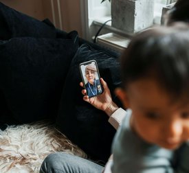 High angle view of female pediatrician assisting woman through video call on smart phone at home