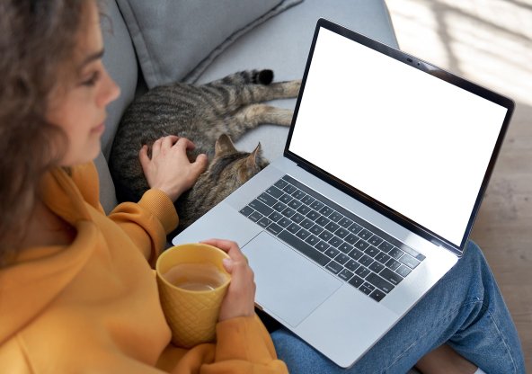 Kvinna som sitter vid sin laptop och dricker kaffe