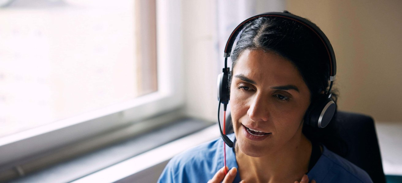 Female doctor wearing headset and having discussion over video call in clinic