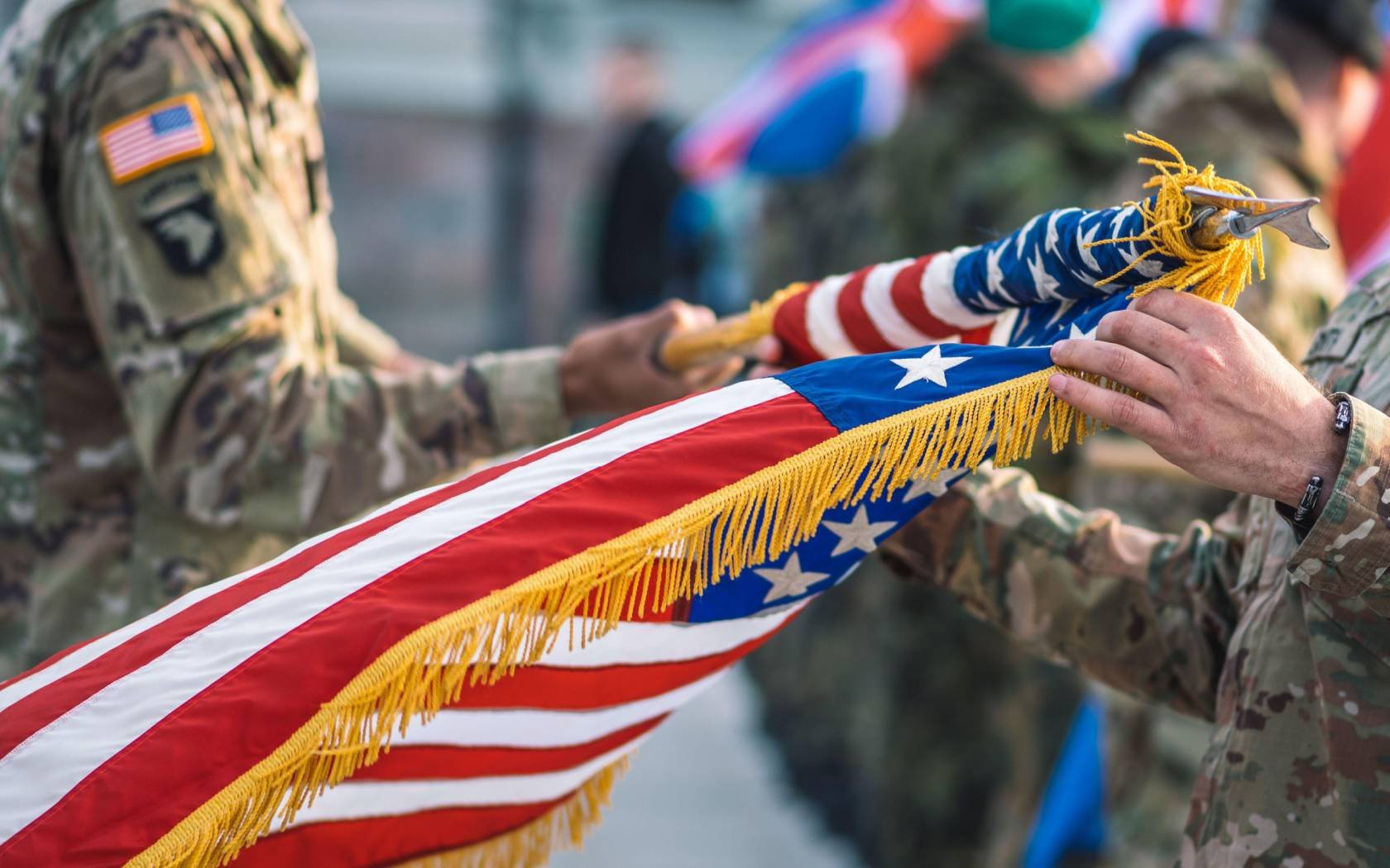 United States soldiers roll up the American flag.