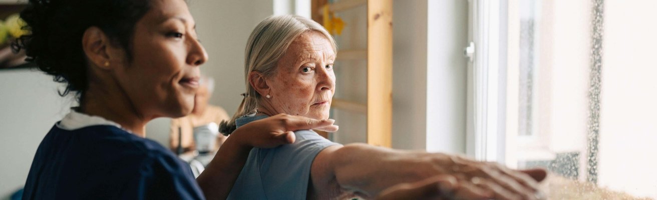 Female therapist helping senior woman with stretching exercise at rehabilitation center