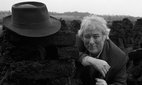 Seamus Heaney at a turf bog in Bellaghy wearing his father's coat, hat and walking stick and additional shots in the Bellaghy bog, 1986. Bobbie Hanvey, photographer. Image bh002815, Bobbie Hanvey Photographic Archives, John J. Burns Library, Boston College.