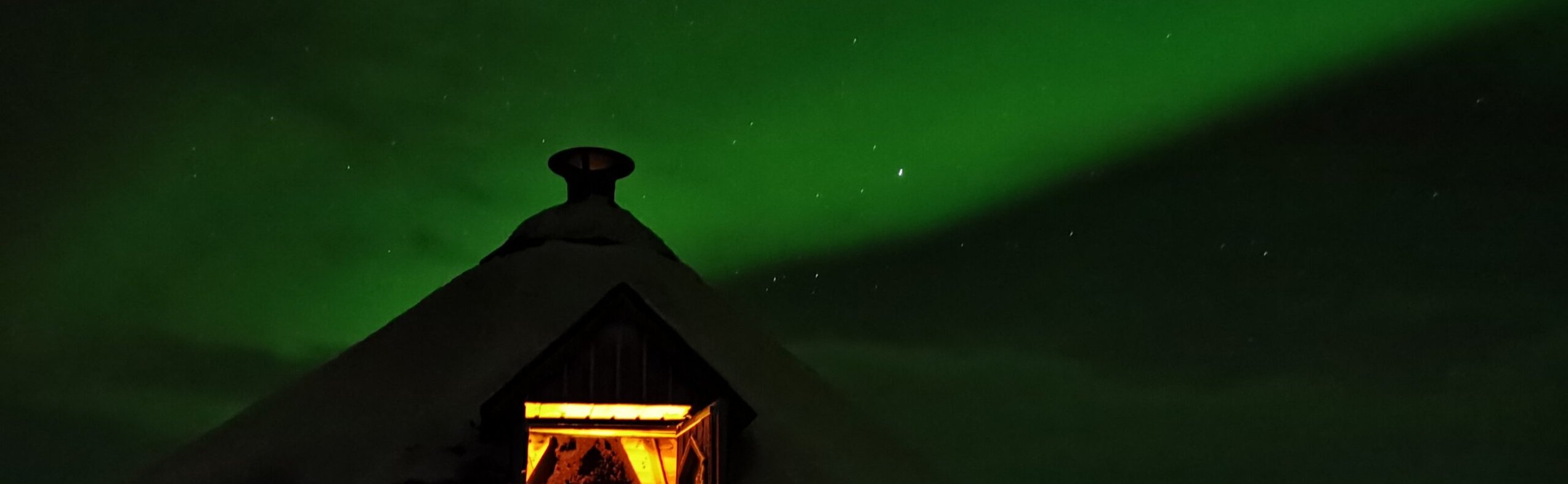 Northern lights over log cabin during autumn night hike in Abisko