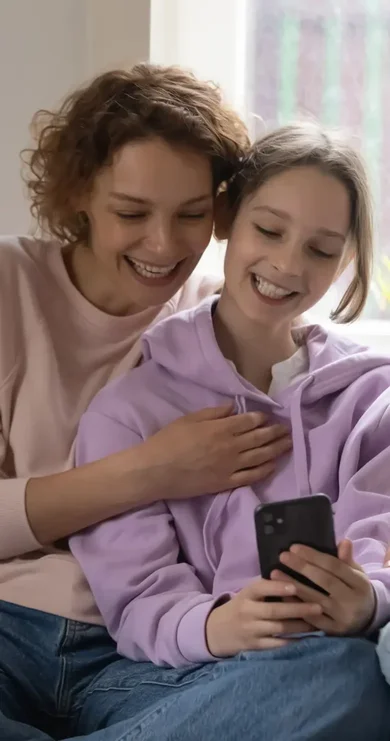 Mamma och dotter sitter och kollar på mobil. Kampen mot näthat.