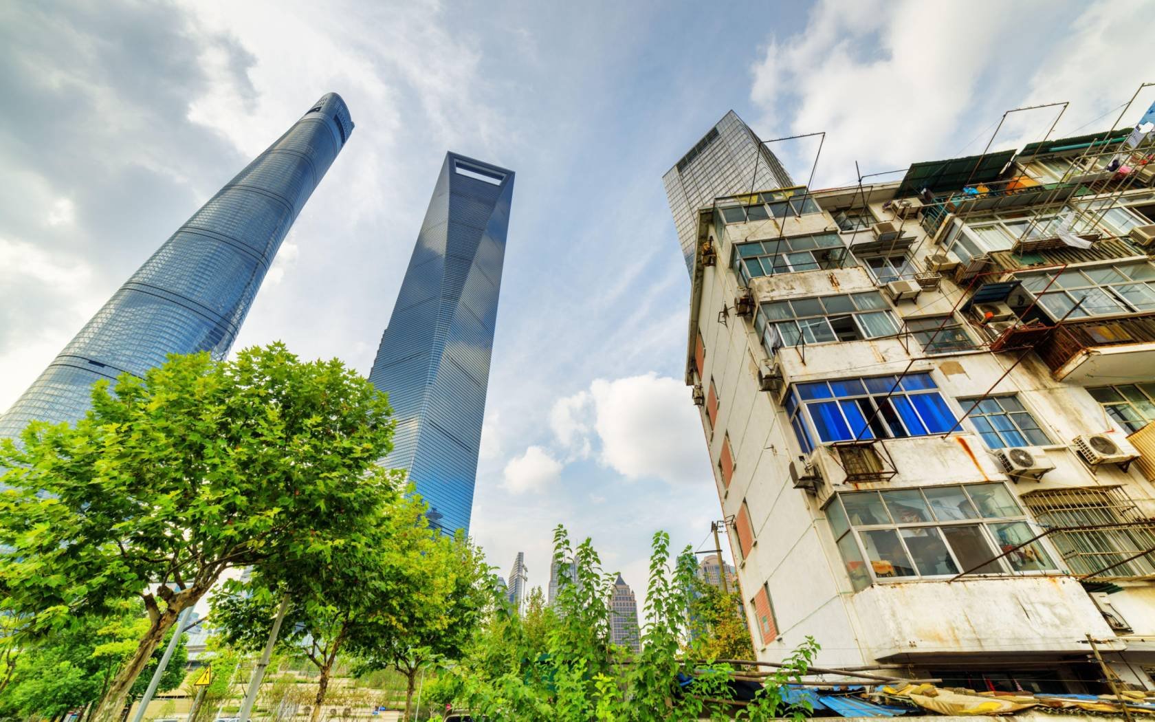 An old house surrounded by modern skyscrapers in Shanghai.
