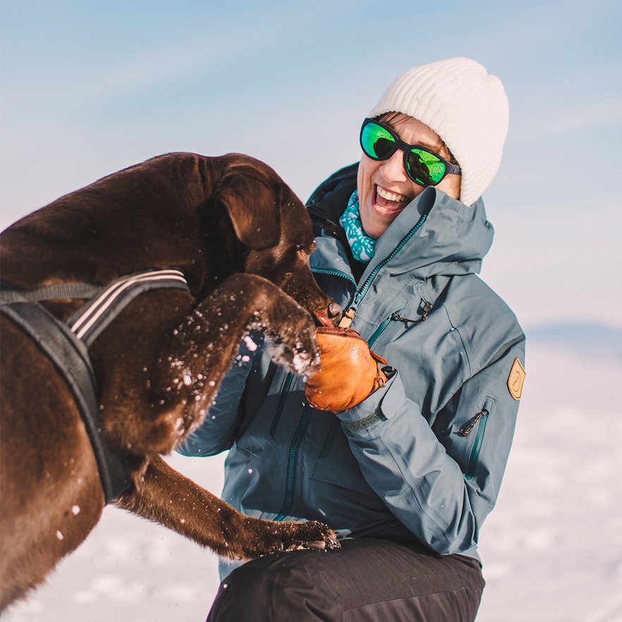 kvinna skrattar medan hon leker med sin labrador