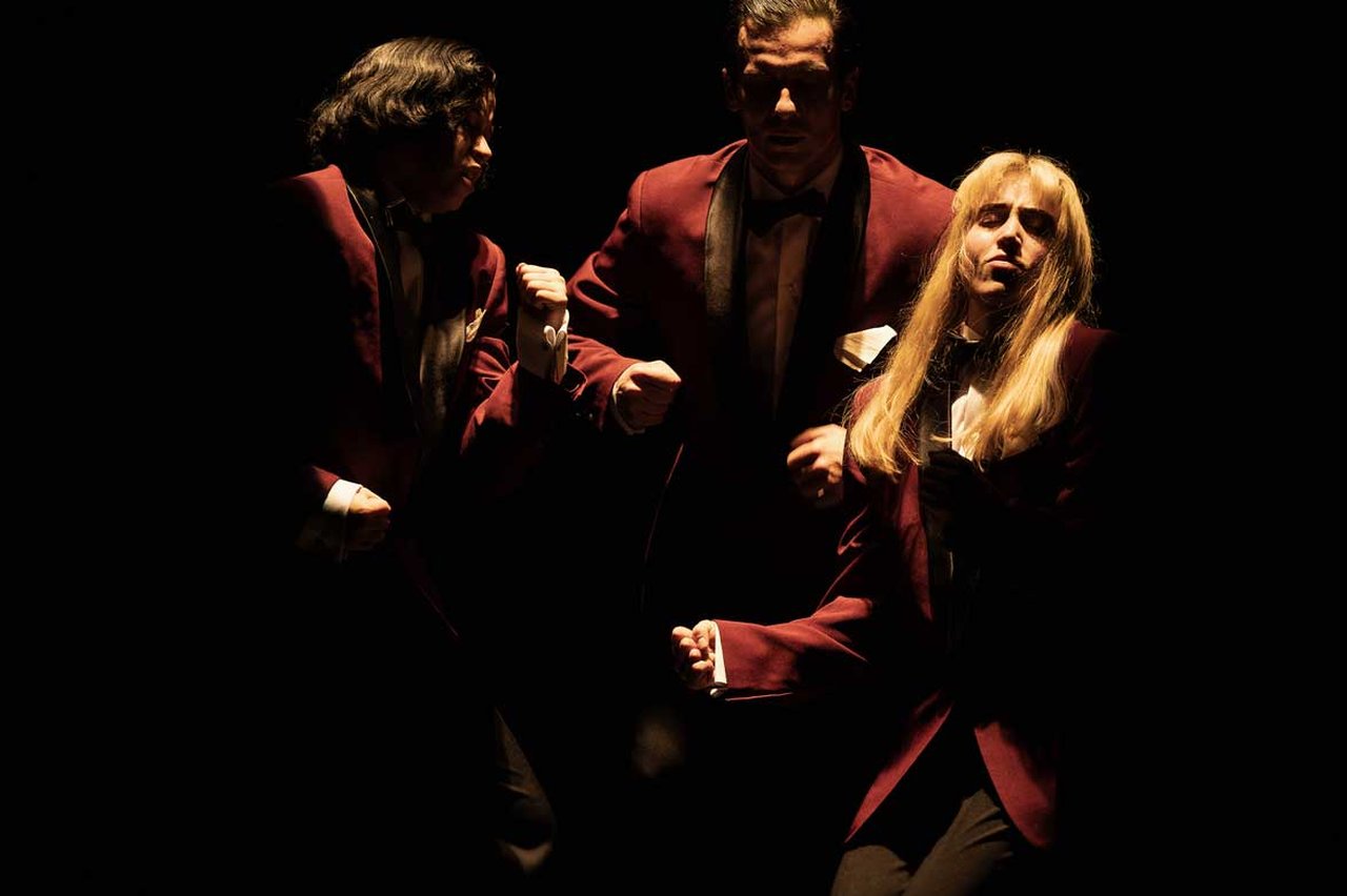 Tre personer i röd smoking från föreställningen Burn Baby Burn.