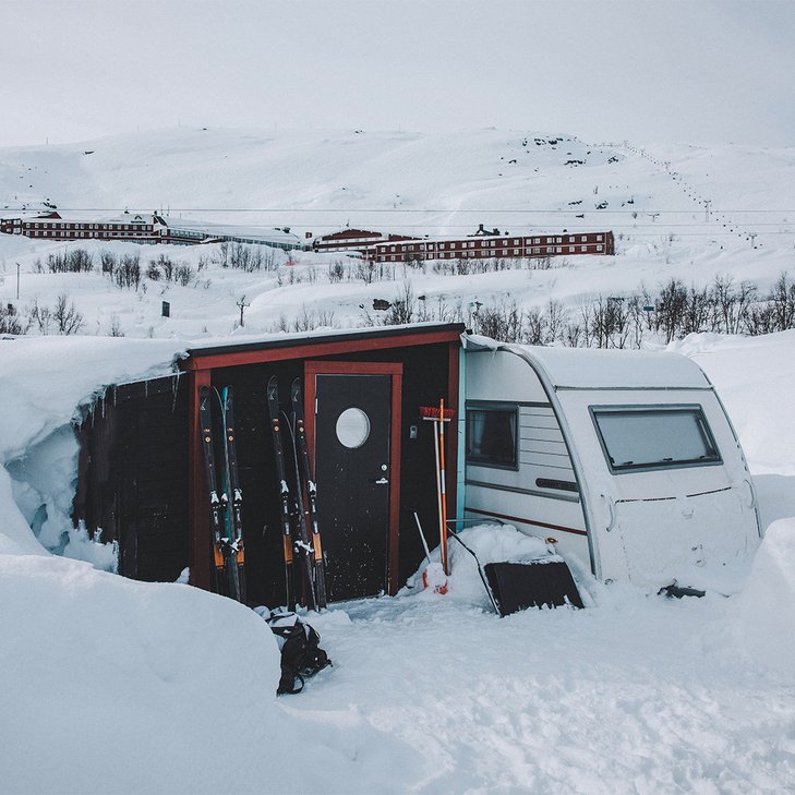 skidor lutade mot f&ouml;rstugan till sn&ouml;omgiven campingvagn