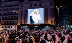 A crowd looks at the cover of Rosalia's new album, 'Lux', in Madrid.