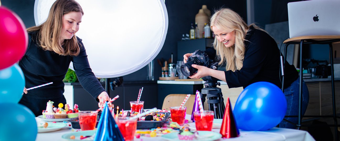 to spoon-ansatte i matstudio tar bilde av et dekket bord