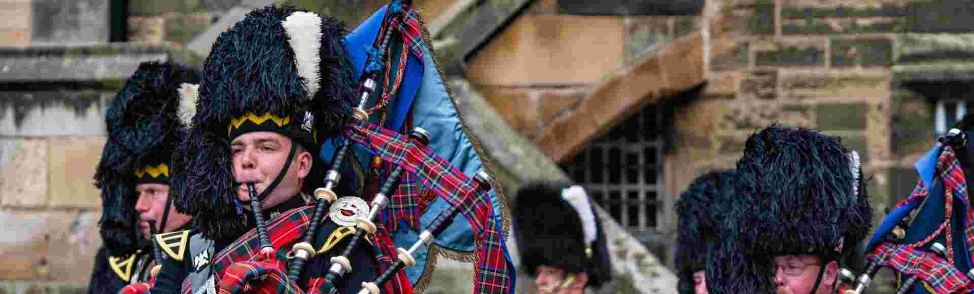 Royal Scots Guards military pipers playing bagpipes in kilt uniforms at Edinburgh Castle in a military ceremony, Scotland, UK.
