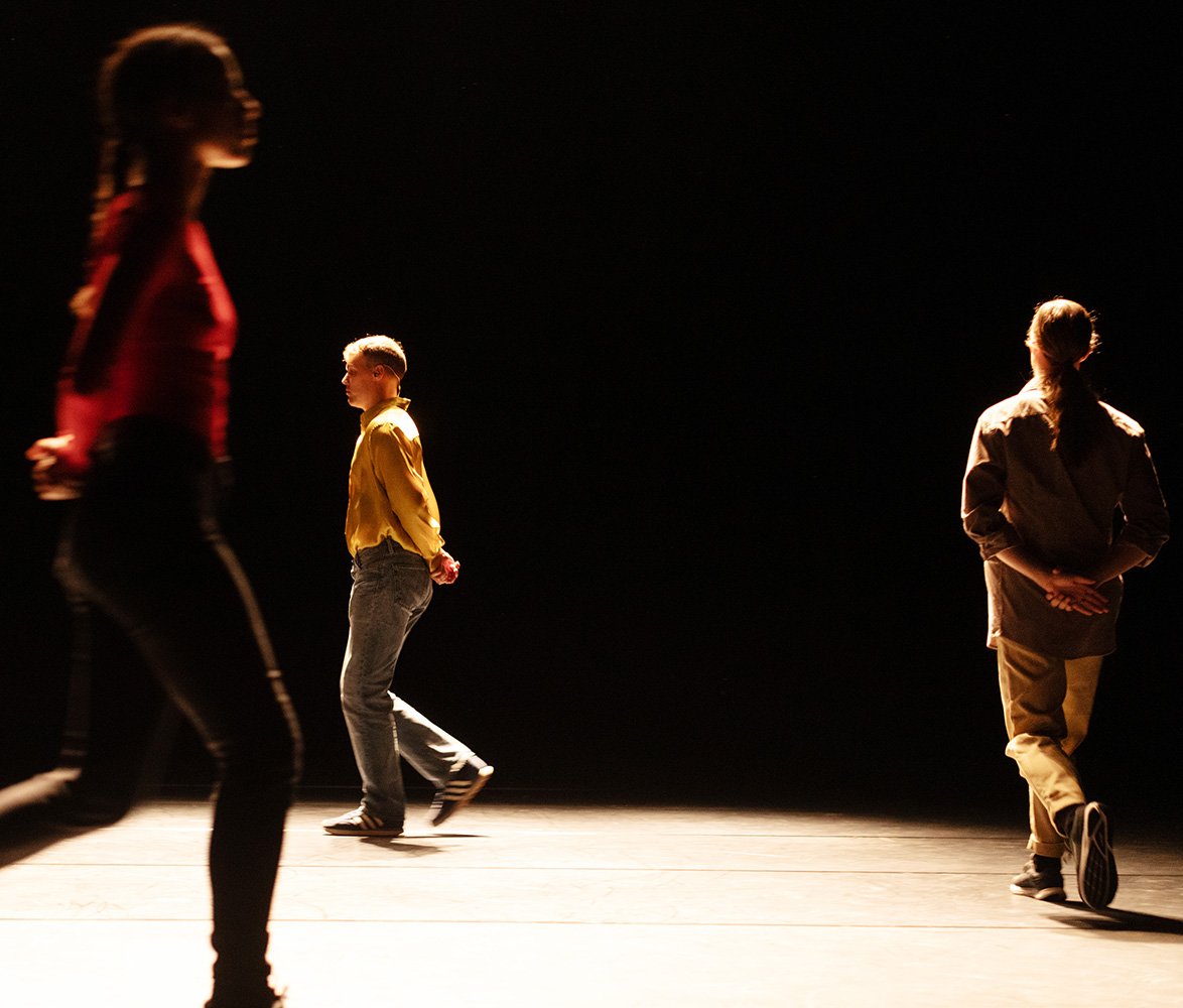 Tre dansare går runt på en scen.