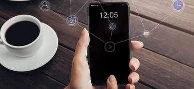 Hand som håller i mobiltelefon + kaffekopp