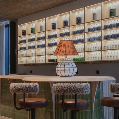 Hernö Gin baren på plan två med fyra barstolar och hyllor fyllda med olika Hernö Gins