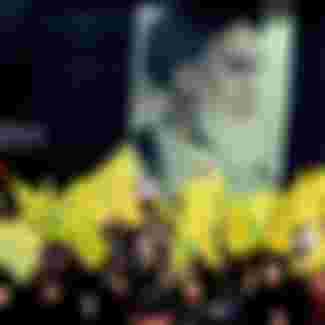 Supporters of the pro-Iranian Lebanese Hezbollah group wave the party flags in front of a poster of late Iranian leader Ayatollah Khomeini during a ceremony in Beirut.