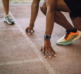 Low section of man kneeling at starting line on running track