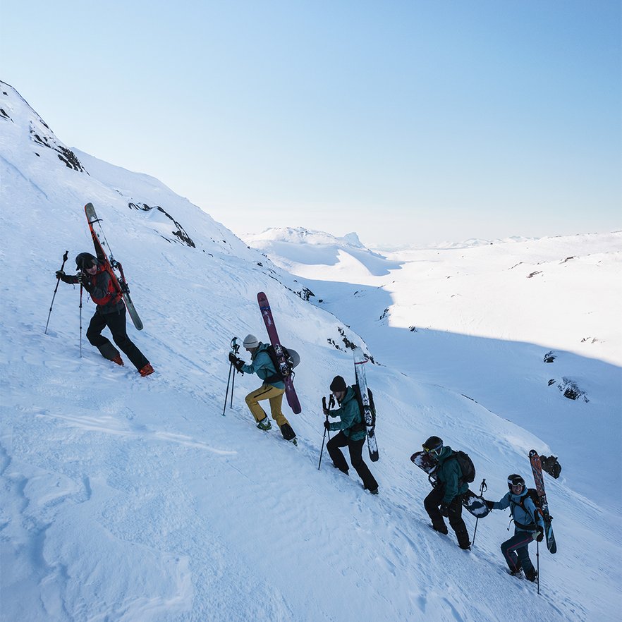 fem personer kl&auml;ttrar uppf&ouml;r Nordalsfj&auml;ll med skidor och snowboard p&aring; ryggen